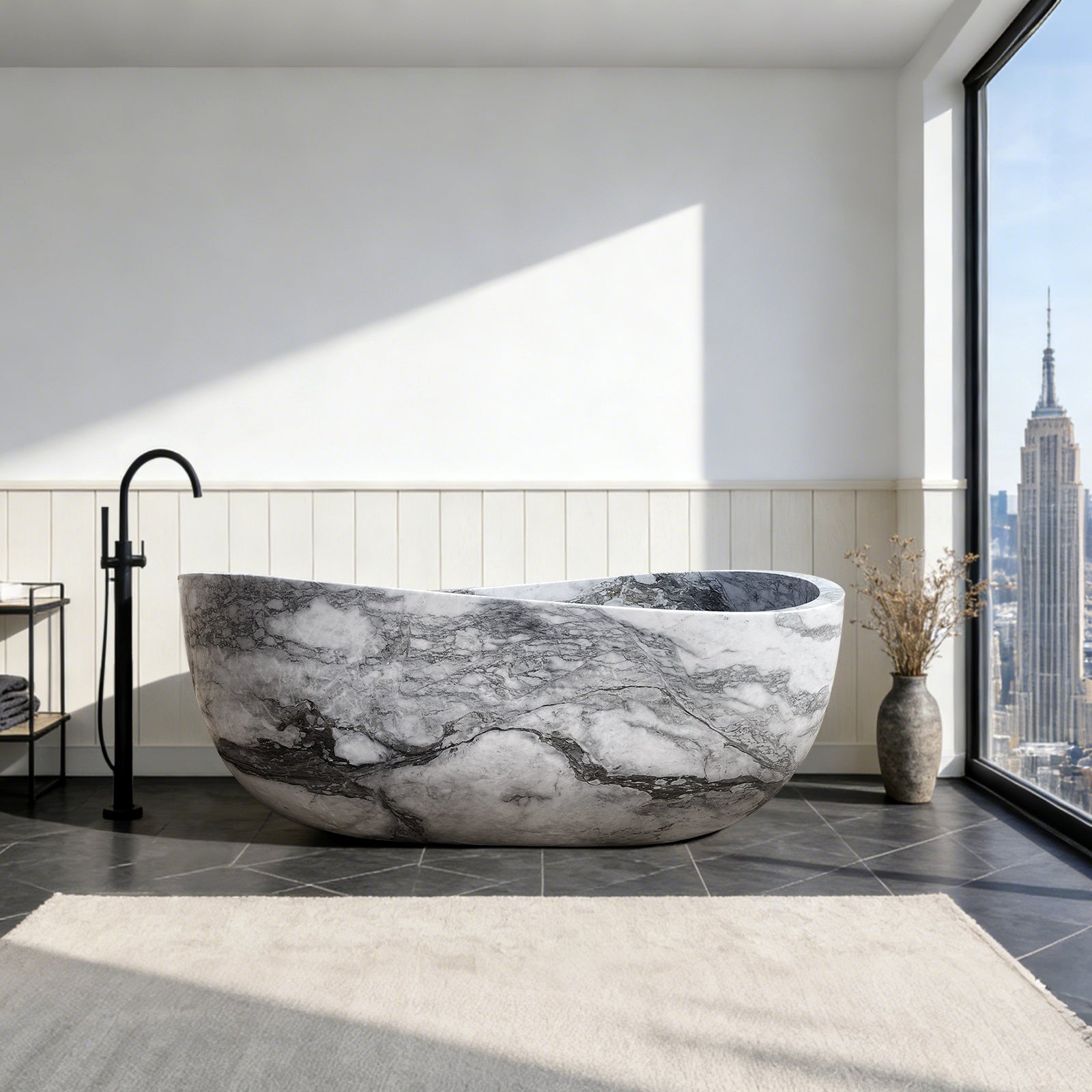 Freestanding oval natural stone bathtub with dramatic black and white marble veining, paired with a black floor-mounted faucet in a modern bathroom with city view.